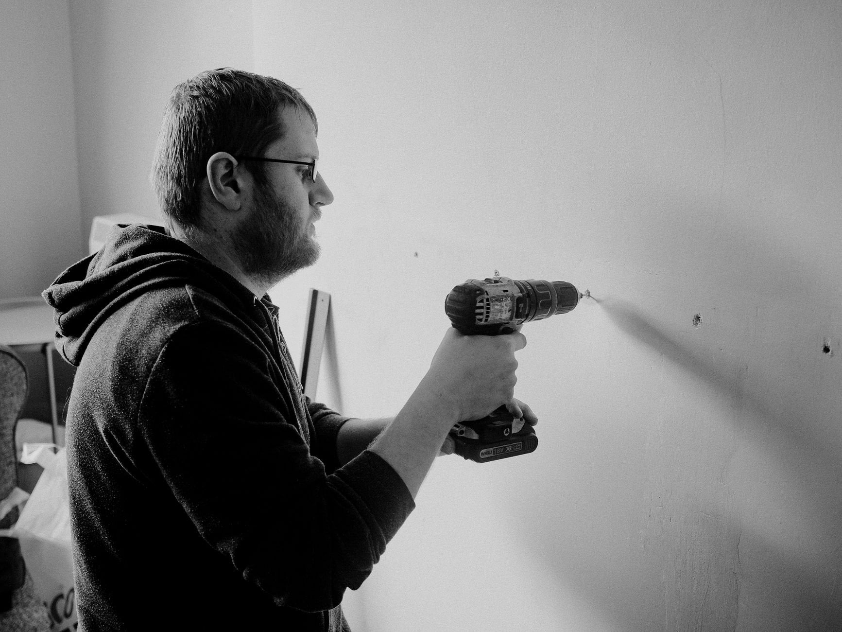Man using a power drill to repair a wall inside a home