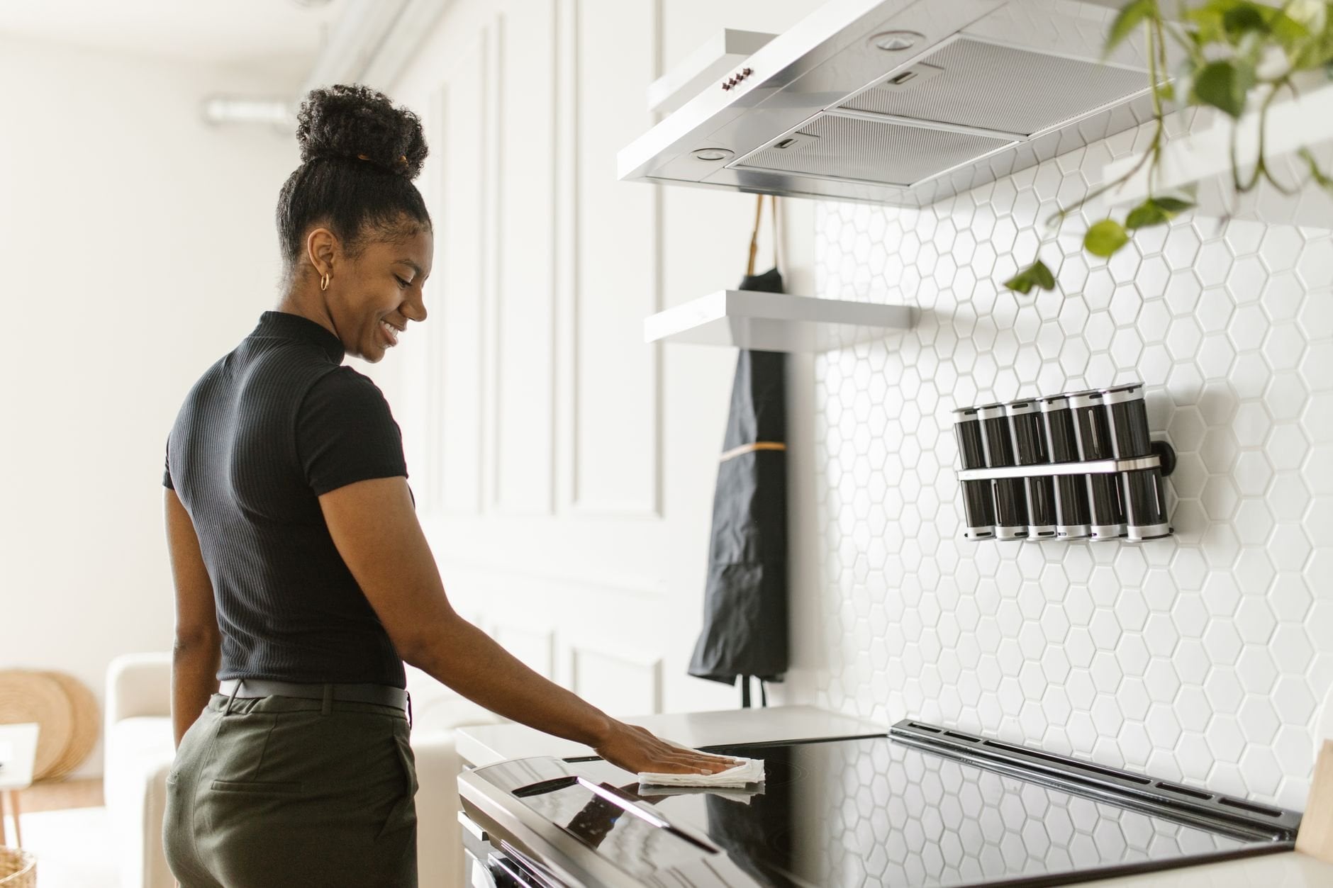 A woman cheerfully cleans a bright modern kitchen